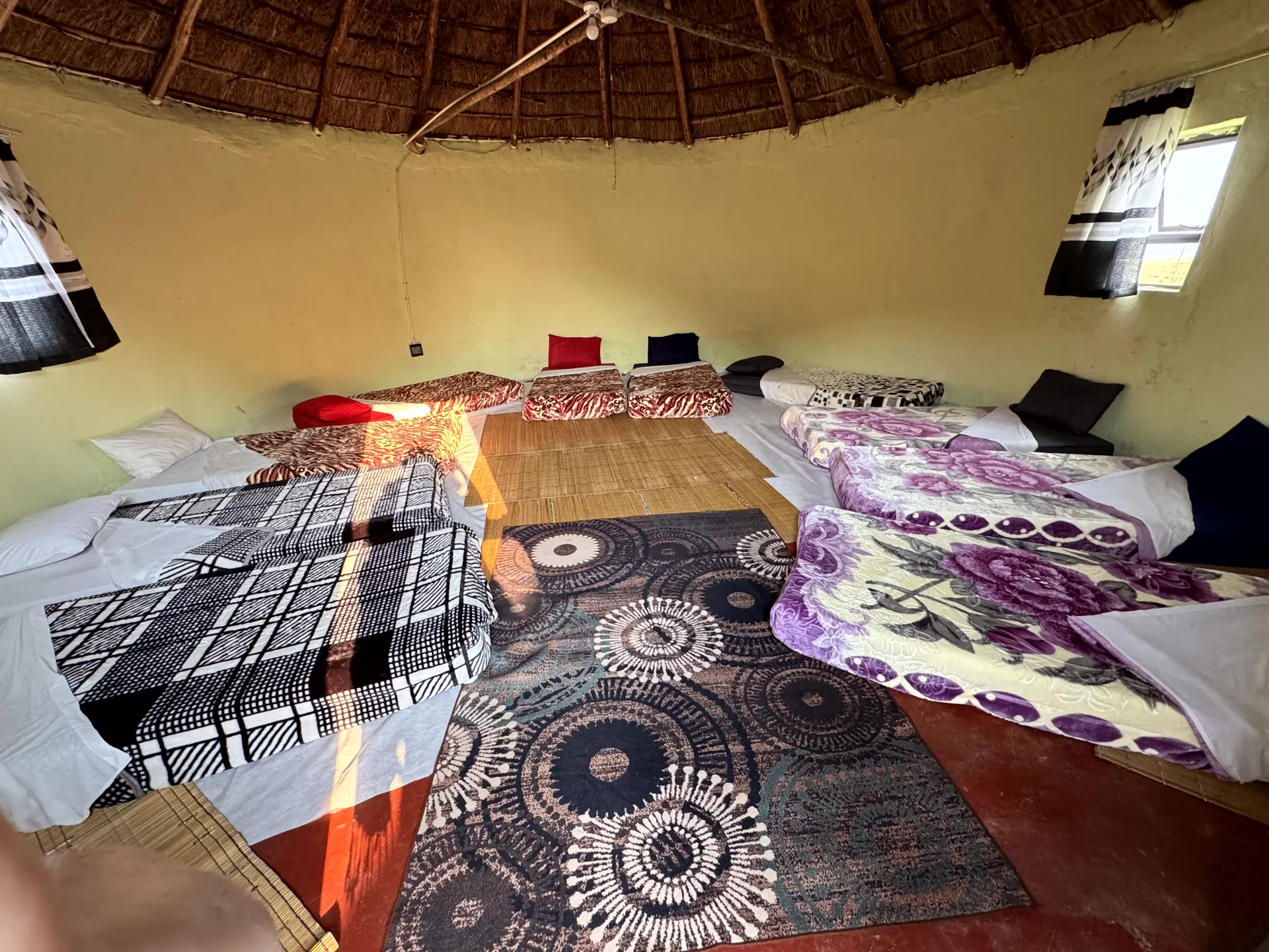 Spacious rondavel interior with multiple beds and patterned rugs
