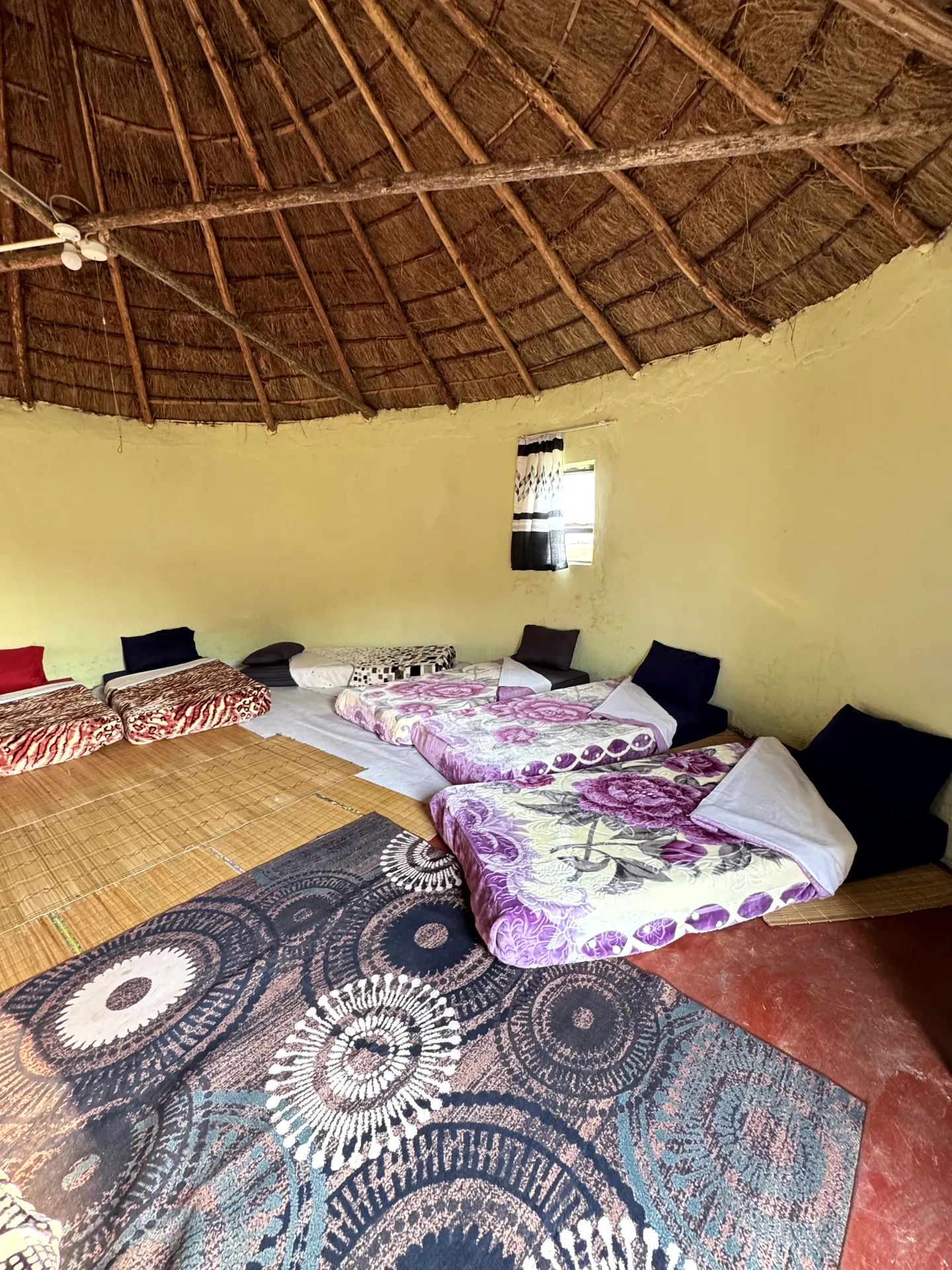 Traditional thatched-roof hut interior with colorful bedding
